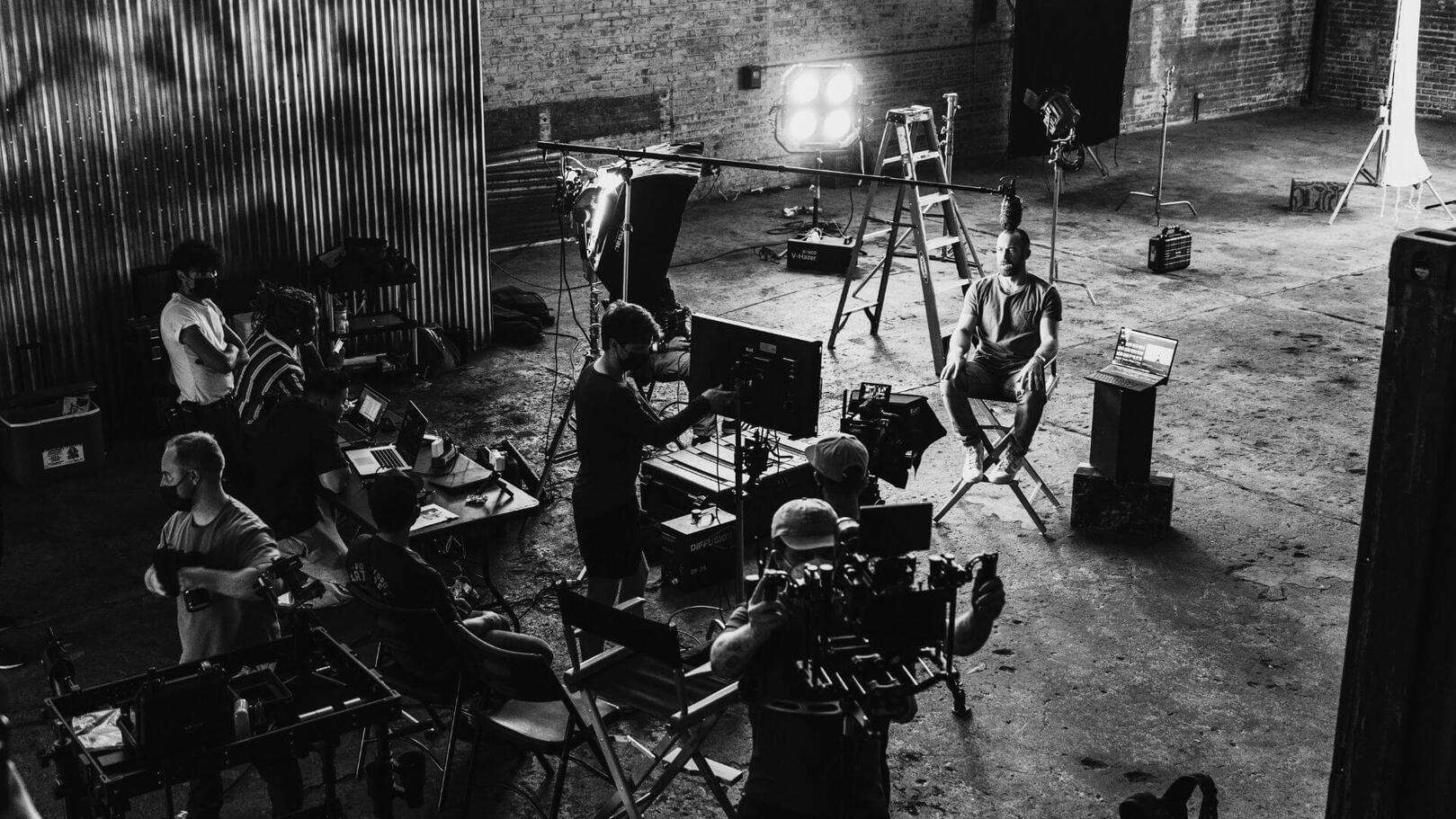 Coordinamento e Logistica di Set — Allestimento e Flussi di Lavoro | Jessica Lima Vista dall'alto di un set cinematografico in allestimento con luci da studio, sedia da regia, monitor e troupe al lavoro sul campo.