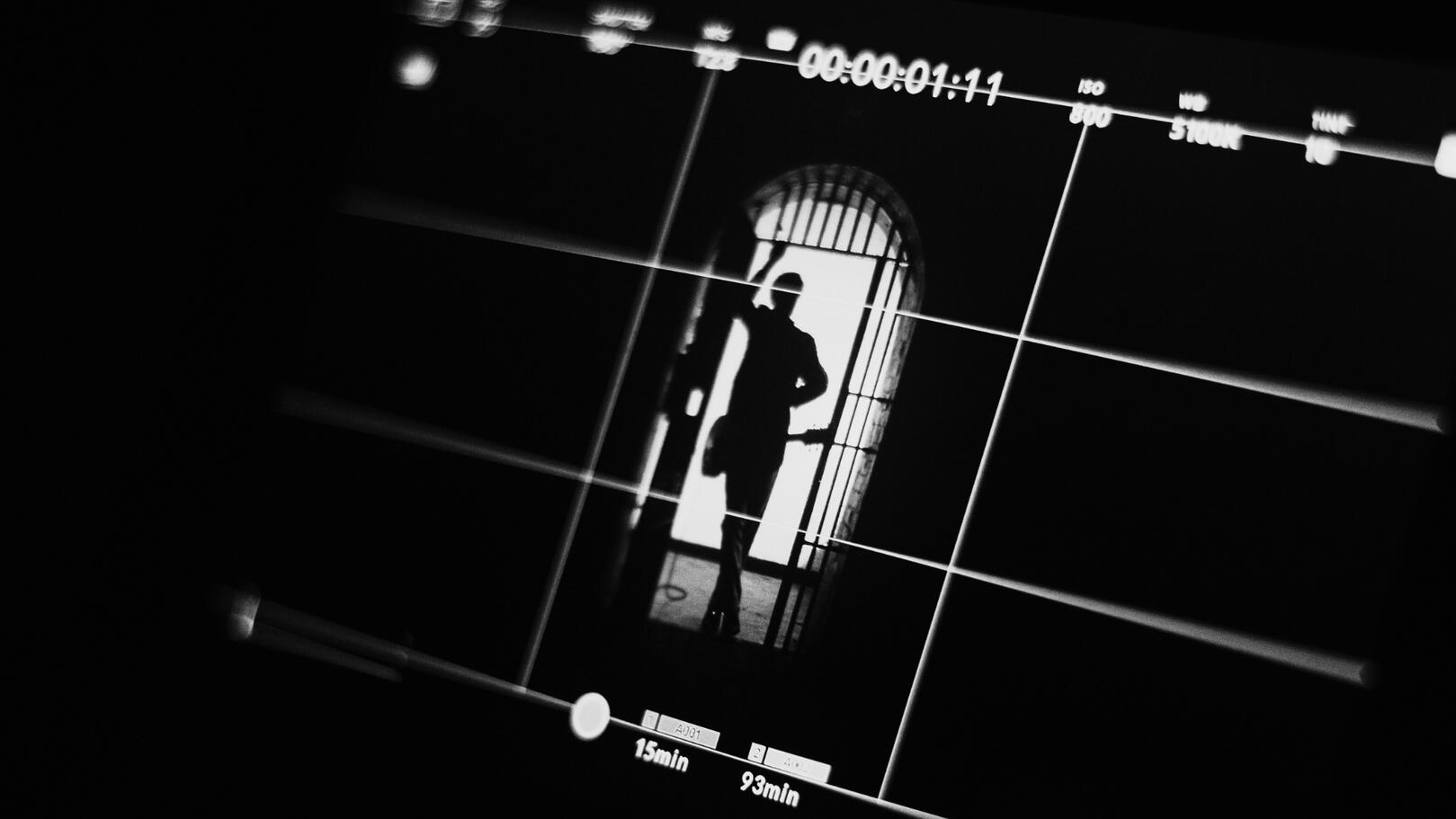 visione-inquadratura-cinematografica Monitor di regia sul set cinematografico con inquadratura della scena in griglia e silhouette