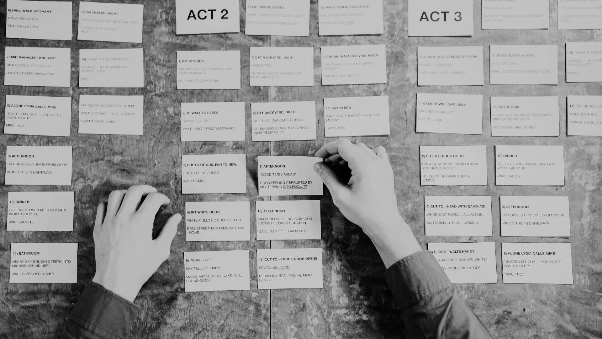 Revisione della Sceneggiatura e Struttura Narrativa — Script Review | Jessica Lima Mani che organizzano ed esaminano schede di pianificazione narrativa divise in atti su un tavolo di lavoro.